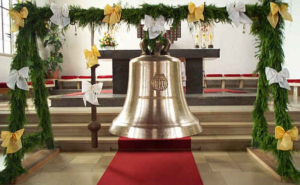 Glocke im Weihegestell vor dem Altar